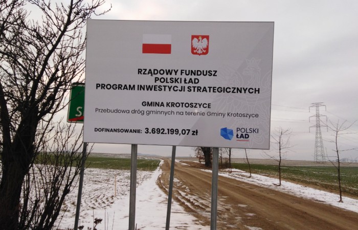 Zdjęcie przedstawia tablice informującą o dofinanosowaniu przebudowy dróg w gminie Krotosztce w ramach programu Polski Ład