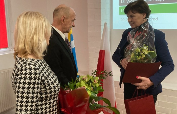 Uczestnicy spotkania wręczją Pani Kierownik kwiaty