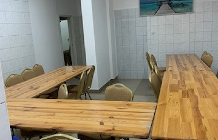 Zdjęcie przedstawia stoły oraz krzesła rozstawione w pomieszczeniu